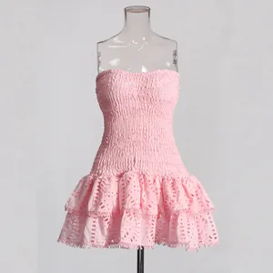 Front view of a pink smocked strapless mini dress with tiered eyelet lace skirt