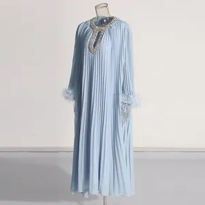 Close-up of elegant pleated maxi dress with rhinestone neck and ostrich feather cuffs