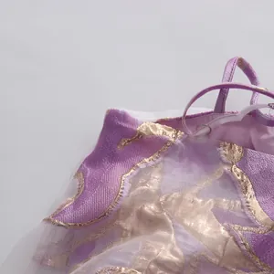 Primo piano del tessuto jacquard floreale viola e oro con velo su un abito a spalline