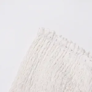 Close-up of white dress showing smocked elastic waist and hollow-out texture.
