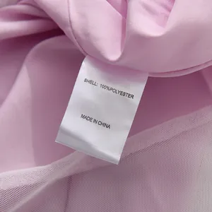 Vista dettagliata dell'etichetta di composizione in 100% poliestere di un abito rosa