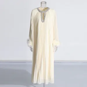 Detailed view of cream pleated maxi dress with crystal neckline and ostrich feather cuffs