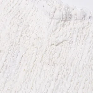 Close-up macro view of high-quality white smocked fabric texture with lace details