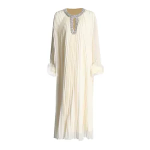 Detailed view of rhinestone neckline and ostrich feather cuffs on white pleated dress