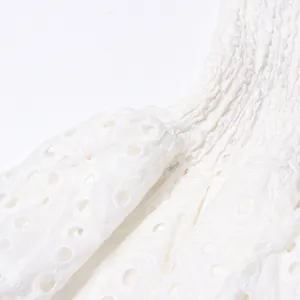 Close-up detail of white eyelet embroidery and smocked bodice on a summer dress