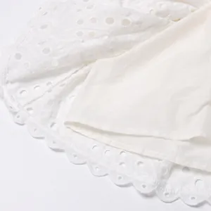 Close-up of white eyelet embroidery and hollow-out detailing on a summer dress hem.