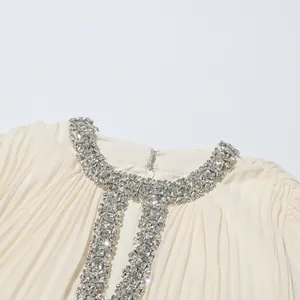 Close-up detail of luxurious rhinestone-embellished neckline on ivory pleated chiffon dress.