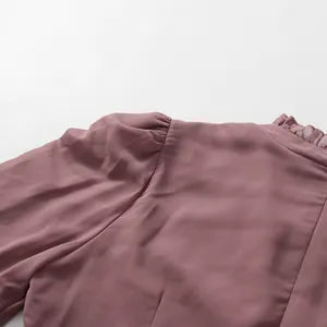 Detail view of the elegant ruffled high collar and puff sleeves on a mauve chiffon dress.