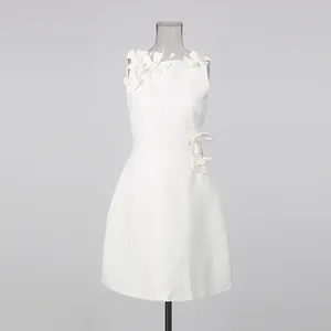 Close-up of white sleeveless dress with elegant 3D floral appliqués on shoulder