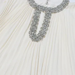 Close-up detail of luxury white pleated dress with rhinestone embellished neckline.