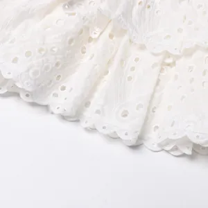 Detail view of intricate white eyelet embroidery and tiered hem on a summer dress