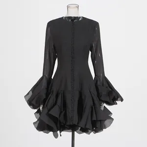 Detail van elegante zwarte jurk met gelaagde ruches aan de zoom en uitlopende klokmouwen
