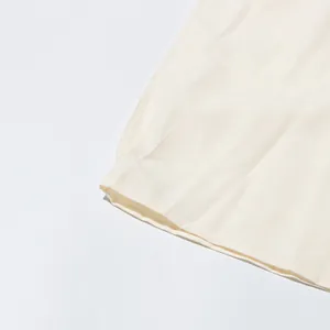 Close-up of high-quality cream fabric hem with neat stitching for women's long dress