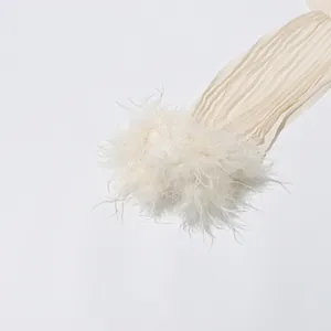 Close-up of elegant ostrich feather trim and pleated fabric detail on cream dress