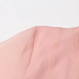 Gedetailleerde close-up van de roze stoftextuur en schoudernaad van een elegante jurk