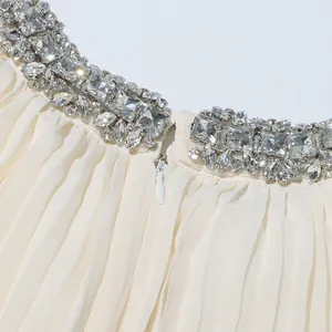 Close-up of elegant pleated dress with sparkling rhinestone neckline and hidden zipper