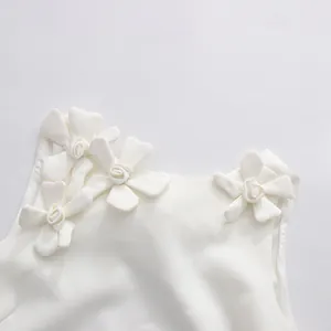 Detailed macro view of elegant white 3D floral appliques on a sleeveless dress neckline