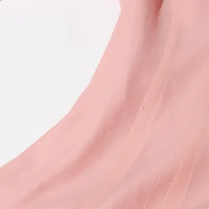 Close-up van de zachte roze stoftextuur op deze elegante Franse midi-jurk voor dames