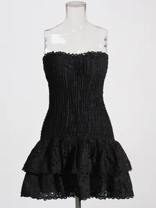 Elegant black eyelet smocked strapless mini dress with tiered ruffle skirt on mannequin