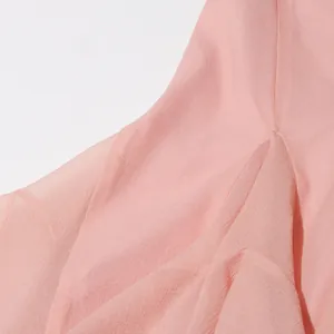 Close-up van de roze jurkstof met ruches die een fijne textuur en elegante stijl laat zien.