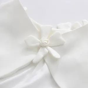 Macro view showing the intricate 3D fabric flower detail on a white sleeveless dress.