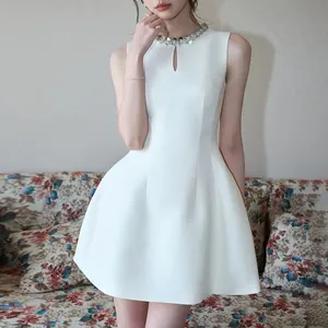 Detailed view of elegant white sleeveless A-line dress with sparkling rhinestone neckline