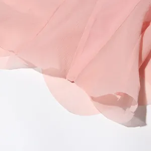 Gedetailleerde close-up van de zachte roze chiffon textuur en de elegante rufflezomen