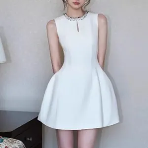 Close-up of elegant white sleeveless mini dress with rhinestone neckline detail.