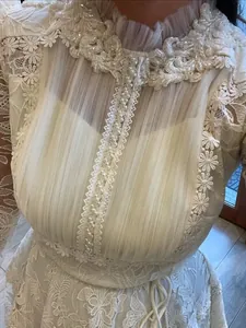 Close-up detail of white lace dress with pearls and floral embroidery