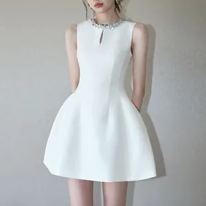 Close-up of elegant white sleeveless mini dress featuring a sparkling rhinestone collar