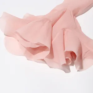 Gedetailleerde macro-opname van de ruches aan de uitlopende mouwen van deze roze chiffon jurk