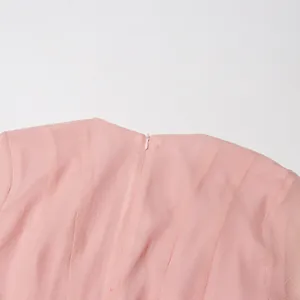 Detail van de onzichtbare rits aan de achterkant van een elegante roze A-lijn jurk.