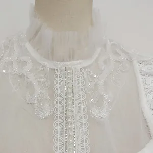 Detailed view of white water-soluble lace dress with pearl buttons and sequins