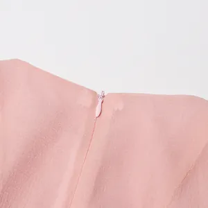 Hoge kwaliteit detailopname van de onzichtbare rits aan de achterkant van een roze jurk