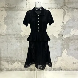 Detailed view of a black knit dress with ruffle waist and lace hem embroidery.