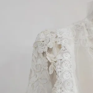 Detailed close-up of intricate white water-soluble floral lace and sequins on a dress