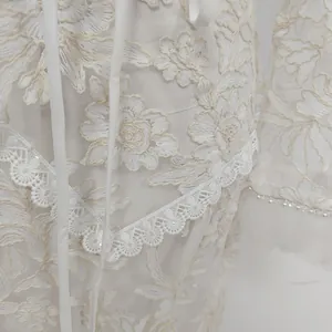 Detail shot of white lace embroidery dress with delicate floral patterns and sequins