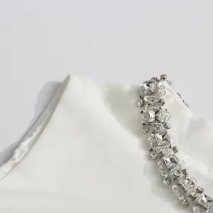 Close-up detail of luxury silver rhinestone and sequin embroidery on white sleeveless dress