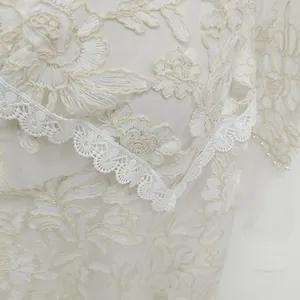 Close-up of intricate white floral embroidery and lace on an elegant formal dress