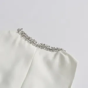 Macro view showing the intricate rhinestone detailing on the elegant white dress neckline.