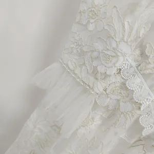Close-up detail of white floral embroidery and pearl trim on French style lace dress