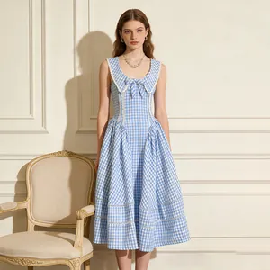 Detalle de un vestido midi de cuadros azules con cuello marinero y lazo decorativo frontal