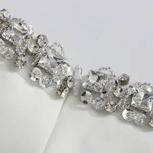 Detailed close-up of premium sparkling rhinestone and sequin embroidery on white dress
