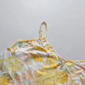 Detail of adjustable spaghetti strap and yellow floral print on a white summer dress