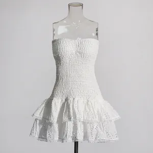 Detail van witte strapless gesmokte mini-jurk met ruches en geborduurd zoom