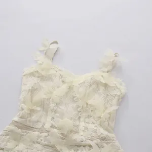 Close-up of white lace dress with 3D butterfly embroidery and spaghetti straps