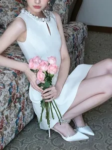Elegant white sleeveless dress with rhinestone neck, shown with a pink rose bouquet
