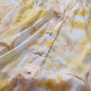 Close-up of pearl buttons and yellow floral pattern on a romantic chiffon dress.