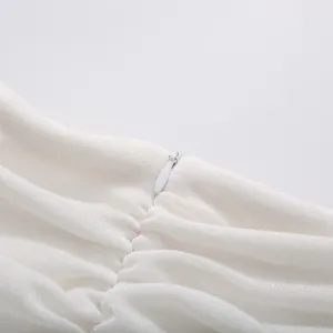 Detailed view of the invisible zipper and elegant ruched fabric on a white cocktail dress