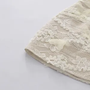 Detailed macro shot of heavy lace embroidery and 3D floral patchwork on dress